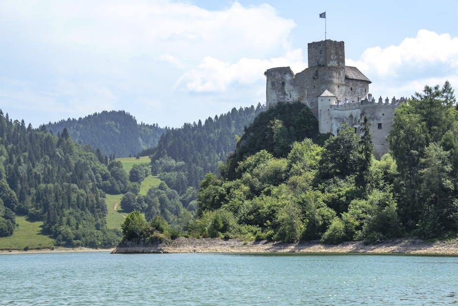 Czorsztyn Castle atop lush hills by a serene lake under a bright sky, a historic Polish landmark.