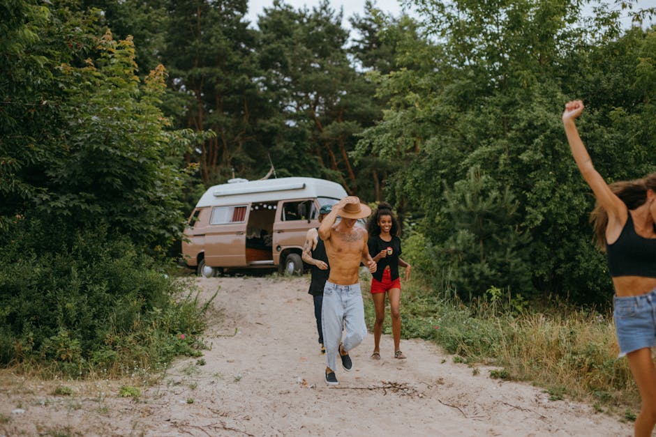 A group of friends having fun near a camper van in a lush forest area.